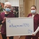 2 nurses holding up sign