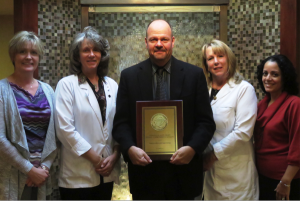 man holding award next to 4 women