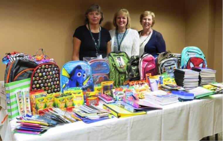 3 women behind table full of donation supplies