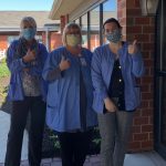 nurses in smocks and masks with thumbs up